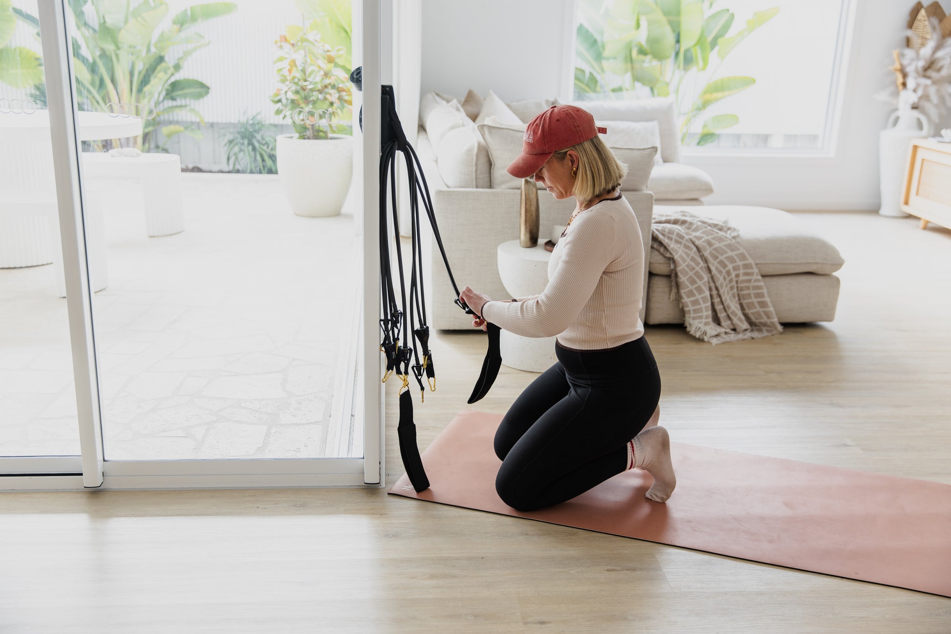 Woman exercising on a pink mat with resistance bands in a bright living room.