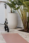 Yoga mat on a stone with plants and Pilates Mini Resistance band exercise equipment in the outdoors