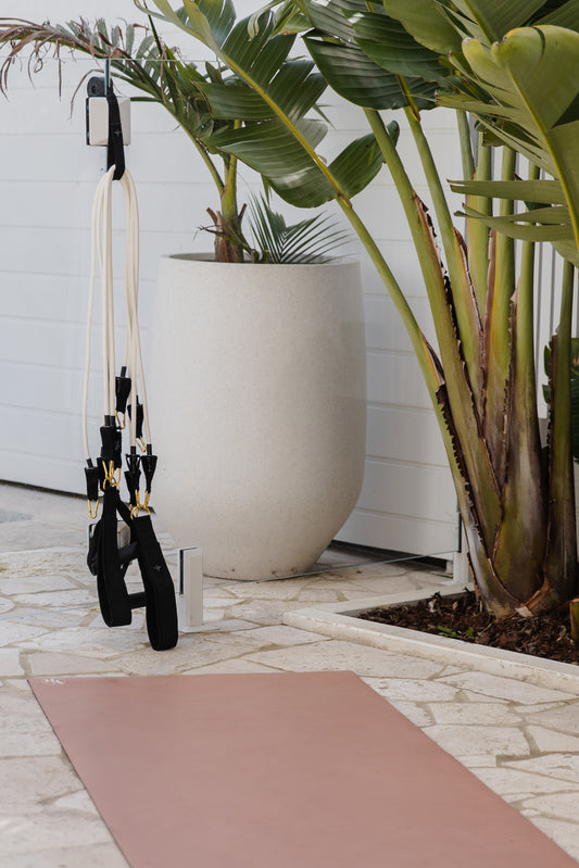 Yoga mat on a stone with plants and Pilates Mini Resistance band exercise equipment in the outdoors