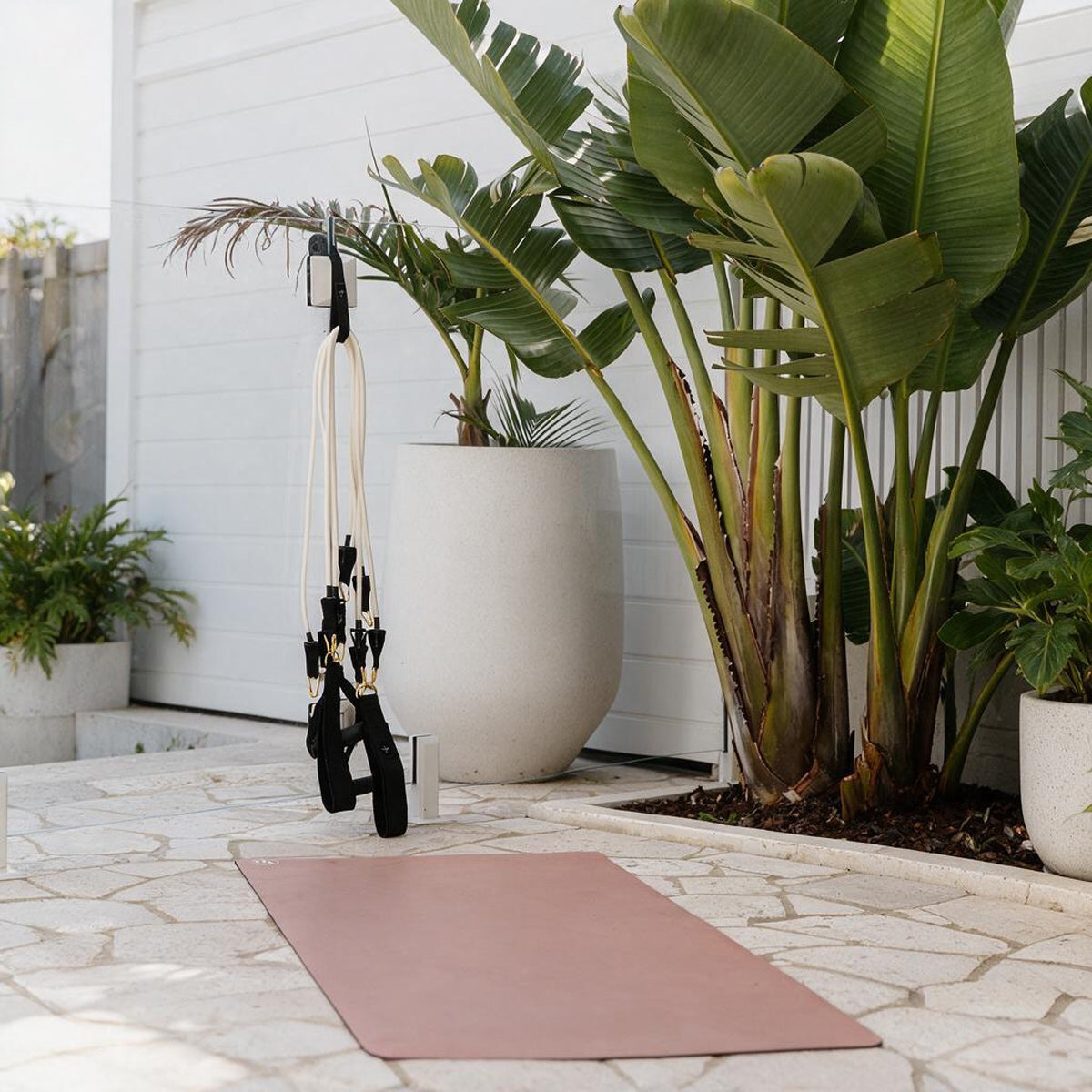 Yoga mat on a stone with plants and Pilates Mini Resistance band exercise equipment in the outdoors