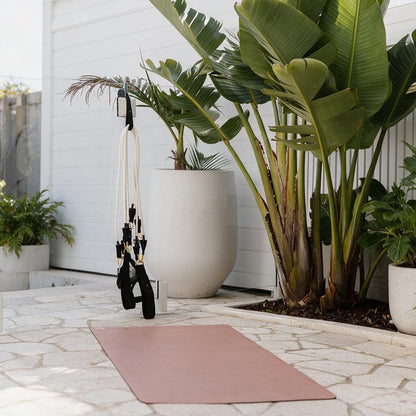 Yoga mat on a stone with plants and Pilates Mini Resistance band exercise equipment in the outdoors